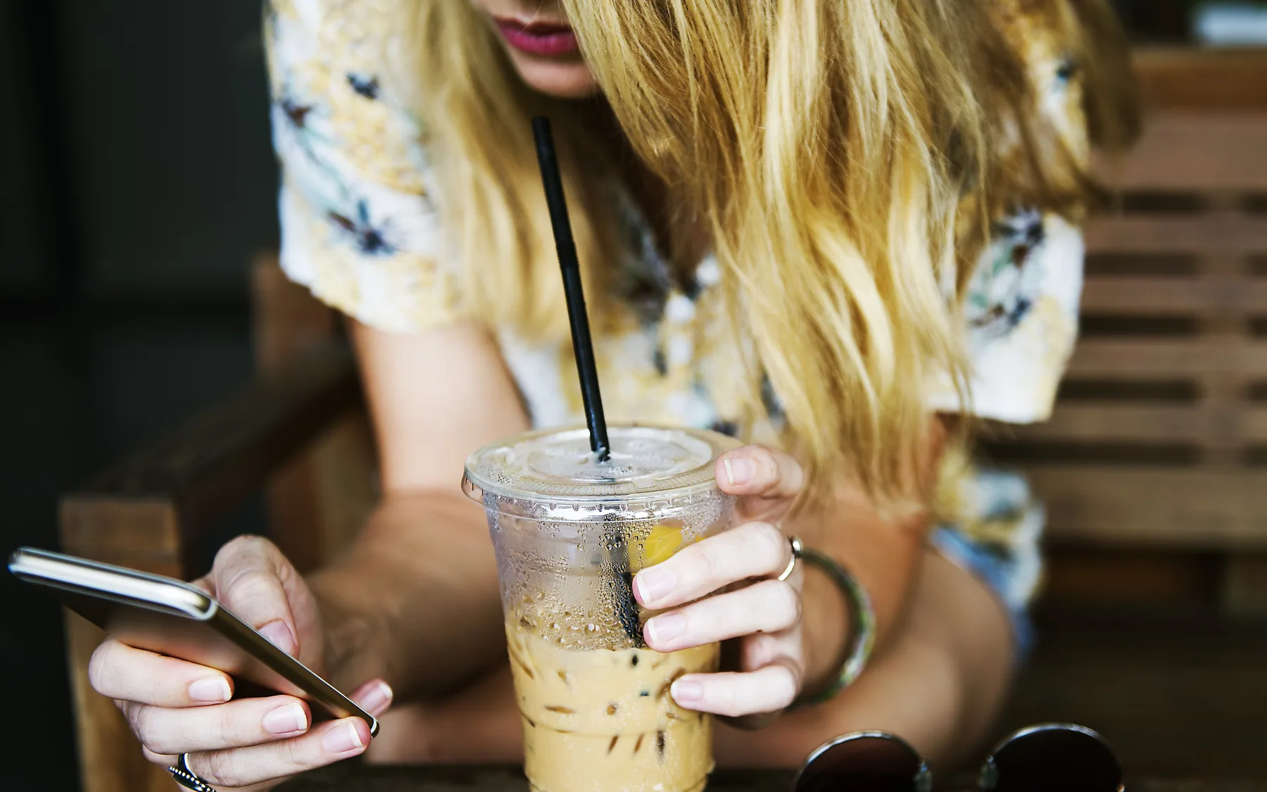 Someone scrolling a phone over an iced coffee